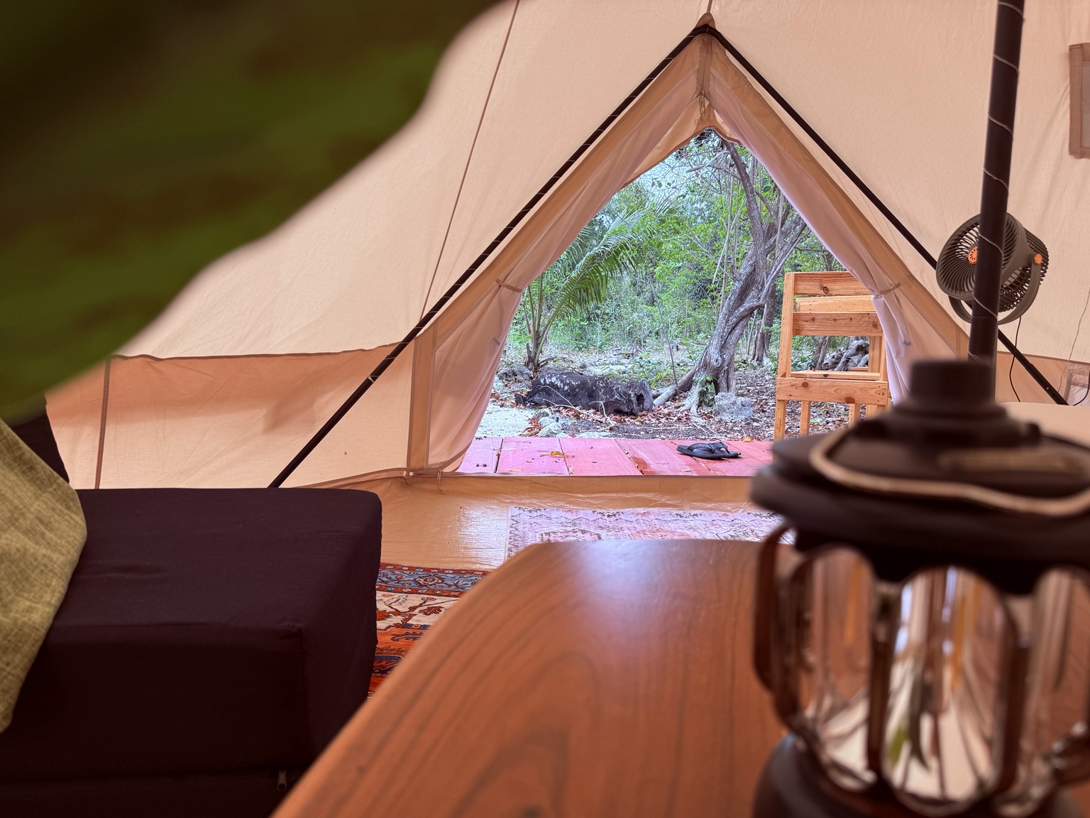 Lantern and table inside the glamping tent with a view outside.